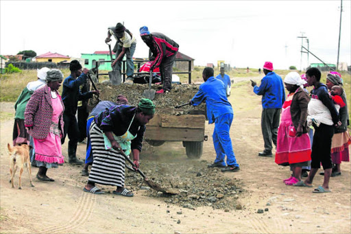 TAKING ACTION: Elderly women lead the way as the community of Tshaba village in Tsholomnqa fill potholes and level uneven parts of the road to the village, after attempts to receive help from the government failed Picture: by SIPHE MACANDA