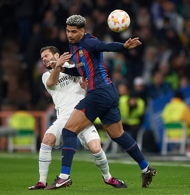 Real Madrid's Nacho (L) vies for the ball with Ronald Araujo of Barcelona