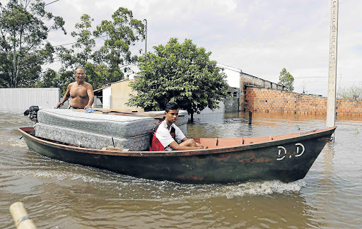 FLOOD FATE: Paraguayans remove their belongings by boat from their flooded houses near the Paraguay River, in Asuncion on Sunday. More than 150 000 people have had to evacuate their homes in the bordering areas of Paraguay, Uruguay, Brazil and Argentina due to flooding in the wake of summer rains brought on by El Nino Picture: REUTERS/Jorge Adorno