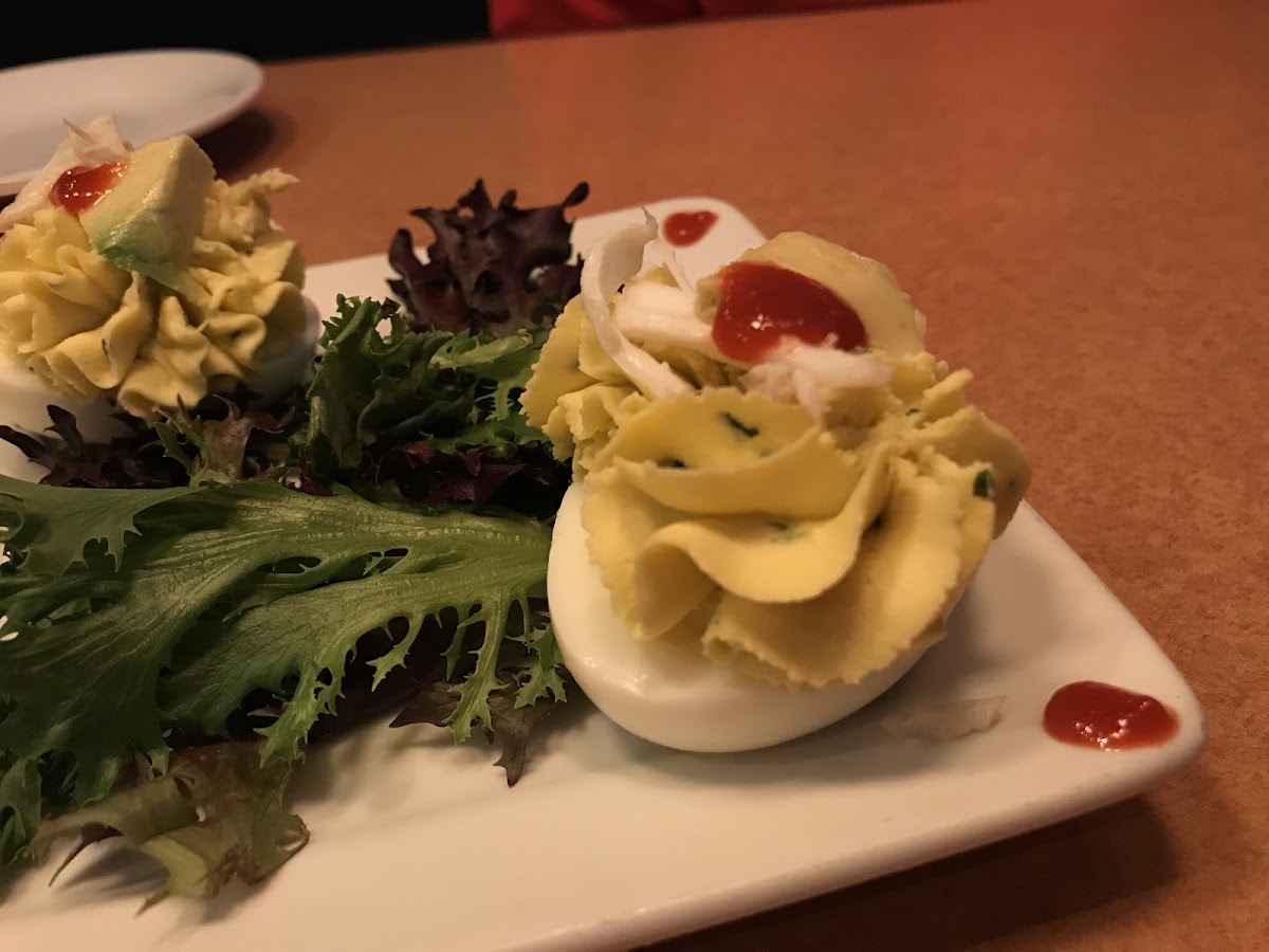 The avocado deviled eggs topped with crab meat and sriracha served as an appetizer.