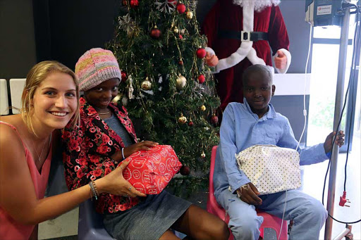 EARLY CHRISTMAS: Border Canoe Club member Jenna van Wyk, left, hands Frere oncology ward patients Emihle Ndumela and Avuyile Mei their presents at the annual CHOC ward party Picture: SIBONGILE NGALWA