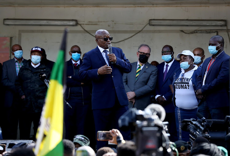 Jacob Zuma flanked by his supporters after appearing at the Pietermaritzburg high court to face charges of corruption, fraud, money laundering, racketeering and tax evasion.