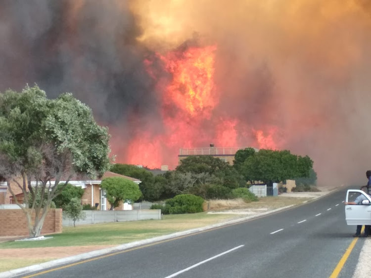 Flames roar behind a house in Franskraal, near Gansbaai on the Western Cape's Overstrand coast, on Friday January 11 2019.