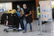 Passengers arrive at Cape Town International Airport on March 12 2020 wearing face masks to prevent being infected with the coronavirus.​ 