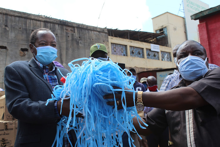 Nyeri Senator Ephraim Maina and county commissioner Loyford Kibaara hand face masks to grassroots leaders for distribution in villages at Whispers Park in Nyeri town on Saturday, May 23, 2020.