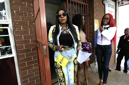 Uyanda Mbuli walks out of court while Joyce Molamu looks at her.