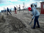 Siyahlala residents dig trenches to bury water pipes for the informal settlement