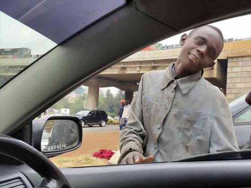 A street boy begs from a motorist in Nairobi.