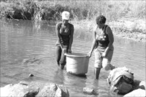 DIRTY WATER: Matodzi Magwala, 21, and Dimakatso Telekisa, 36, both from Hanesengani, one of the affected areas of Sekhukhuni, are forced to use river water for cooking and washing their clothes. Pic. Elijar Mushiana. 16/01/08. © Sowetan.
