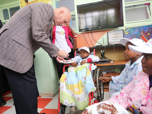 Israeli ambassador to Kenya Noah Gendler feeds a child at the KNH cancer centre on Thursday, August 16, 2018. /CAROLYNE KUBWA