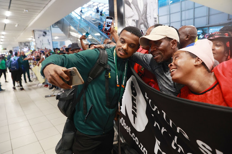 Teboho Mokoena poses with supporters during the national football team’s arrival at OR Tambo Airport in Johannesburg.