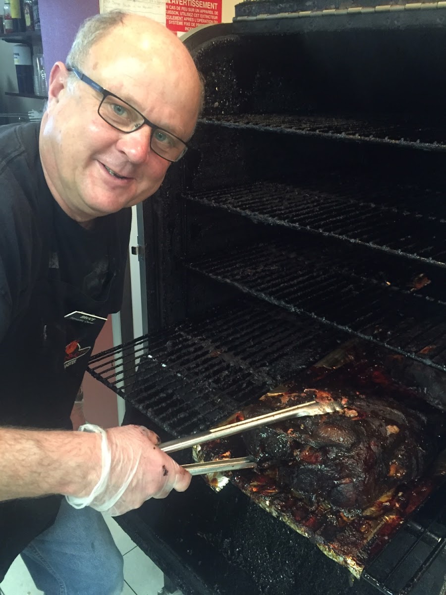Pitmaster pulling a pork roast off our Smoker