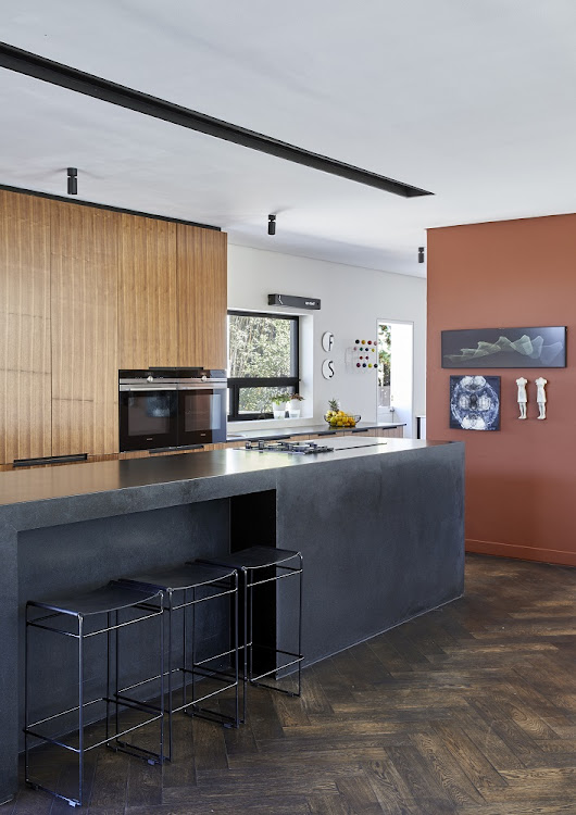 The black Zimbabwean leather granite kitchen island extends into the living area.