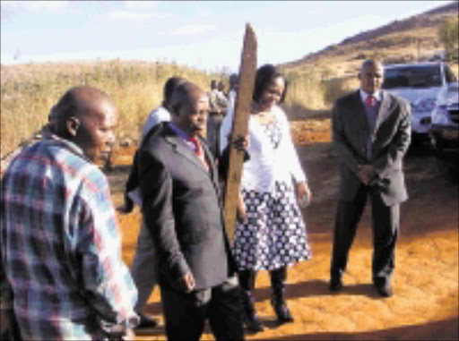 ON SITE: MEC Siphosezwe Masango holding a log that was allegedly used to chase the late Nonyathi Mahlangu. Pic. Alfred Moselakgomo. 20/07/08. © Sowetan.