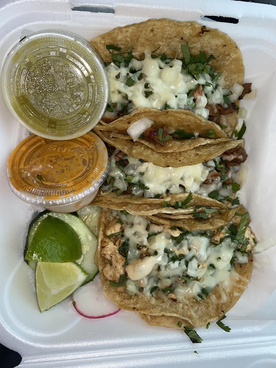 2 al pastor tacos, 1 chicken, topped w cilantro and onion, two side sauces, and limes. I asked for cheese on top.
