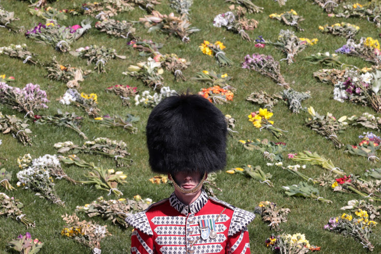 A member of the Guidon, Colour and Truncheon Parties stands in front of a sea of floral tributes that were laid out in the grounds of Windsor Castle ahead of the funeral of Prince Philip.