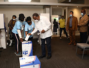 Former ANC deputy president Kgalema Motlanthe is helped by IEC officials to place his ballot papers in the correct boxes after casting his vote at Killarney Country Club in Johannesburg.