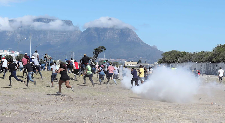 Protesting students at the Western Cape College of Nursing in Athlone, Cape Town, flee as police open fire with stun grenades and rubber bullets.