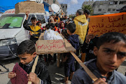 Palestinian children carry banners during a march demanding an end to the war and an end to the famine that citizens suffer from due to the war on March 6, 2024 in Rafah, Gaza.  