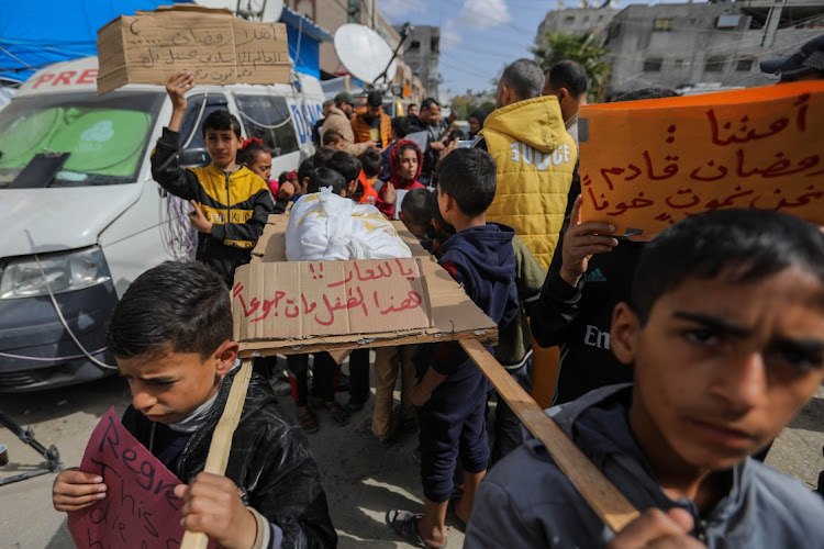 Palestinian children carry banners during a march demanding an end to the war and an end to the famine that citizens suffer from due to the war on March 6, 2024 in Rafah, Gaza.