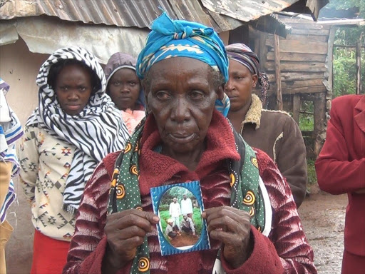 PHOTO/ Grace Kiget holding the photo of her missing son Samwel Kipsang Rotich who has gone missing since the skirmshes between the maasai and Kipsigis communities at Olpusimoru in Narok county./FILE