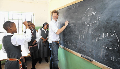 Prince Harry learns sign language from deaf children during a visit to the Kananelo Centre, a project supported by his charity, Sentebale, in Maseru, Lesotho