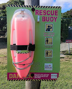 A pink rescue buoy with instructions on how to save a swimmer.