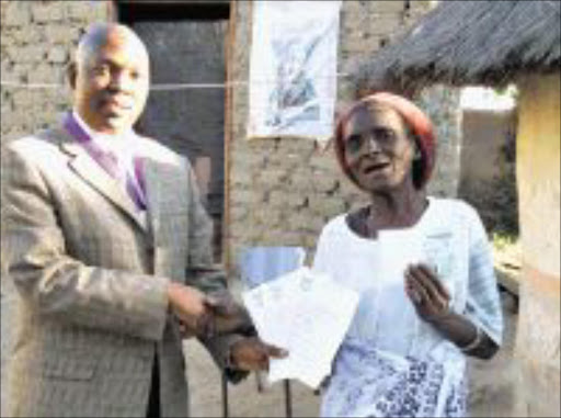 HAPPY ENDING: Home Affairs official Eddie Maphosa hands over a birth certificates and an ID to granny Mokwape Mmola yesterday. Pic: MICHAEL SAKUNEKA. 11/08/2009. © Sowetan.