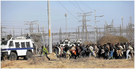 Scene before Marikana massacre. Mineworkers armed with traditional weapons attempt to overrun a police nyala. The confrontation ended with the death of 34 strikers after police opened fire outside the Lonmin Mine in Rustenburg Picture: ALON SKUY