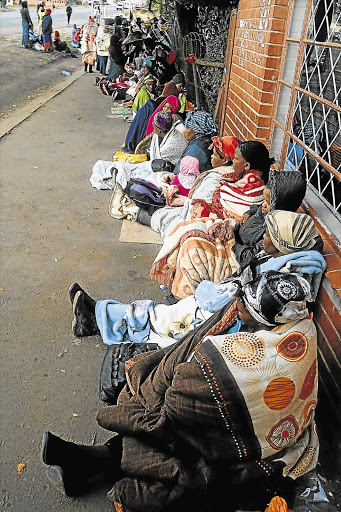 Social grant beneficiaries, mostly women, wait outside a Sassa office. Calls are being made to protect vulnerable people from unscrupulous lenders.