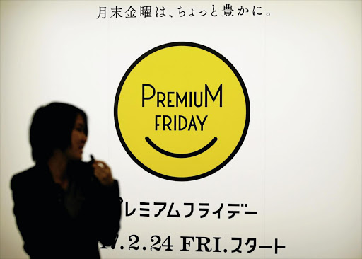 A woman in Tokyo, Japan, walks past the logo of the Premium Friday campaign, which encourages companies to let workers out a few hours early on the last Friday of every month.