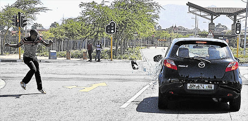 BRICKS FOR BUILDING, NOT THROWING: A student stones a car at the Bellville campus of the Cape Peninsula University of Technology