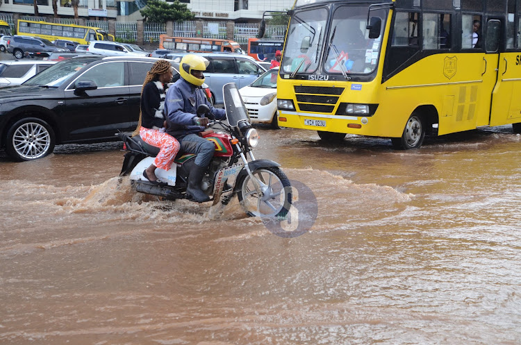Nairobi residents brave the cold weather as they try to access their way home after a heavy downpour on April 24, 2024.