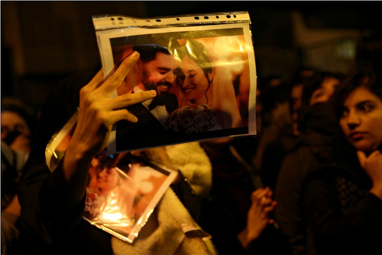A woman holds a picture of newlyweds, victims of the crash of the Boeing 737-800 plane, flight PS 752, as people gather to show their sympathy in Tehran, Iran, on January 11 2020.