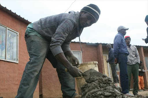A construction worker mixes cement. File photo.