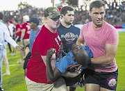 An injured man, believed to be a protester, is carried off the field after demonstrators disrupted a Varsity Cup rugby match between the home team, the Shimlas, and the Madibaz, at the University of the Free State campus yesterday. Infuriated spectators rushed onto the field and attacked the protesters. UFS vice-chancellor Jonathan Jansen said the spectators were both white and black and did not believe the attack was racially motivated. He said the university would go through video footage and would 'take very strong action'. The campus is closed for two days.