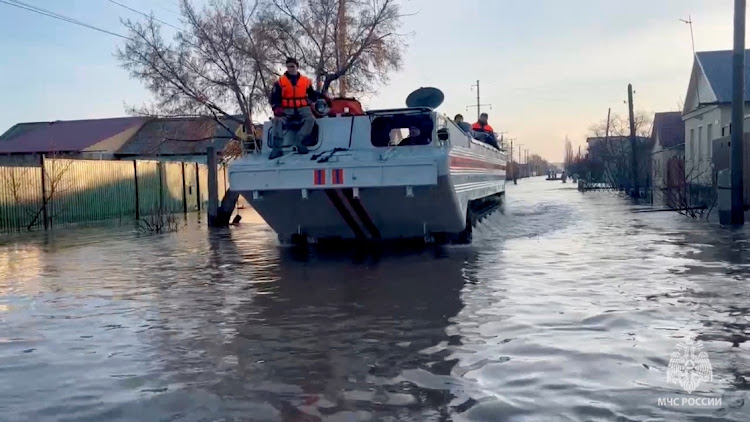 Rescuers search for residents to evacuate as they drive in a flooded residential area in the city of Orsk, Russia, April 6, 2024, in this still image taken from video.