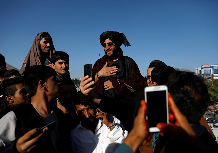 Afghans take picture with a Taliban militant in Kabul, Afghanistan June 16, 2018.