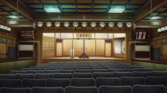 Dark theater stage with red curtains and spotlight