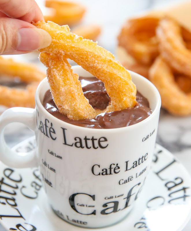 close-up photo of a churro being dipped in chocolate