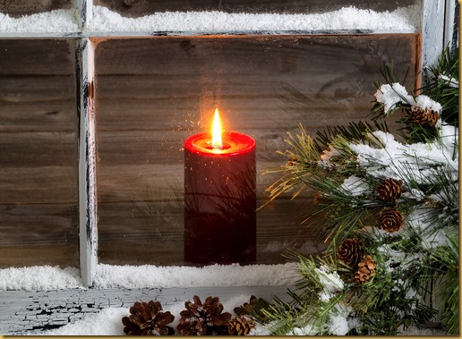 Christmas red candle with snow covered home window and pine trees