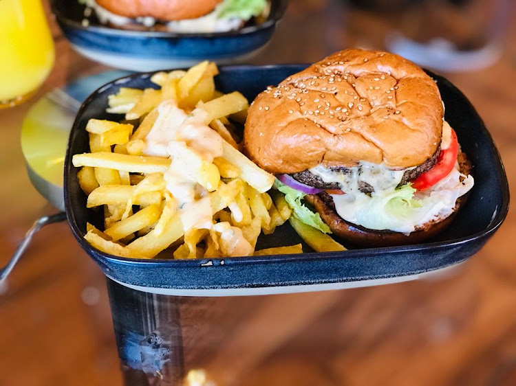 Loaded burger served with fries topped with dipping sauce.