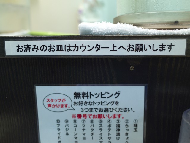 カウンター上に書かれた「お済みのお皿はカウンター上にお願いします」の文字