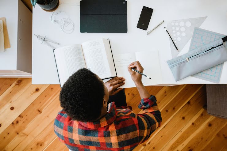 Un jeune homme concentré, assis à son bureau, travaille.