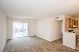 Living room with carpeted flooring, white walls and trim, and sliding door to the outdoor balcony