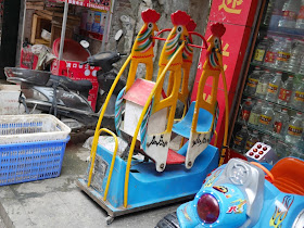 kiddie ride resembling a two-child swing with one seat filled by a house-like object