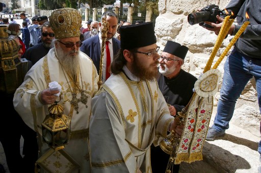 The head of the Greek Orthodox church in Bethlehem, Bishop Theophylactos (L), leads a crowdless 'Holy Fire' ceremony, due to the coronavirus (COVID-19) pandemic, in the West Bank town of Bethlehem on April 18, 2020, on the eve of Orthodox Easter.