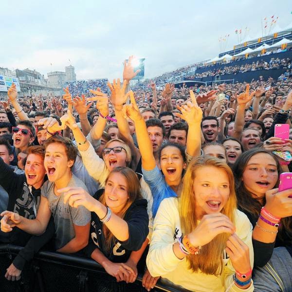 People cheer as they listen to a concert given on the main stage by French rapper Akhenaton of the band IAM (unseen) on July 13, 2014 in La Rochelle, during the Francofolies music Festival.