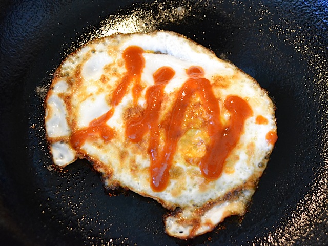 cooked egg in pan with siracha on top 