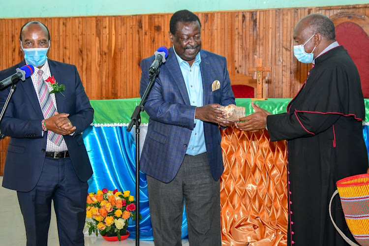 Amani National Congress Party Leader, Musalia Mudavadi (Right) hands over his contribution to Bishop Joseph Mbatia of the Catholic Diocese of Nyahururu. Looking on is Nyandarua Governor, Francis Kimemia.